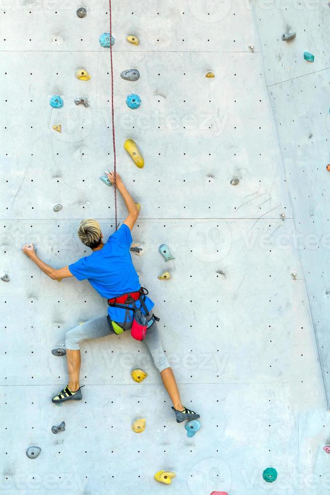 una mujer está escalando un muro de escalada foto