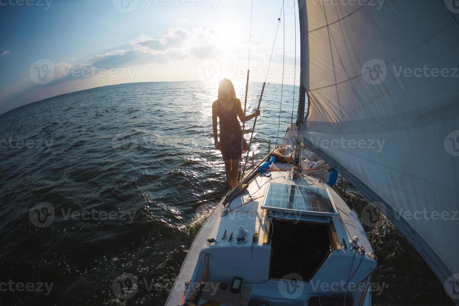 A girl in a dress stands on a sailing yacht photo