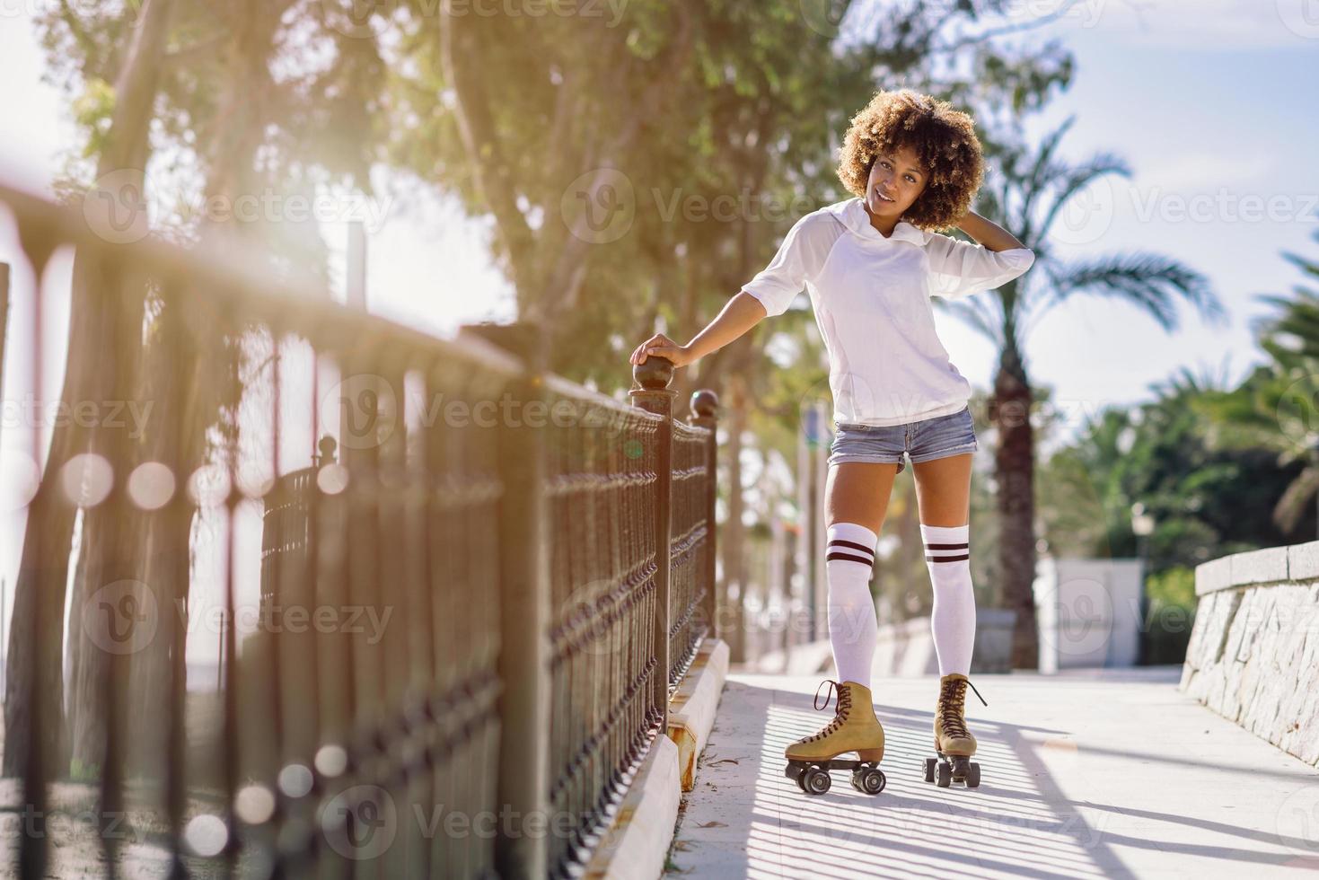 mujer negra, peinado afro, en patines montando cerca de la playa. foto