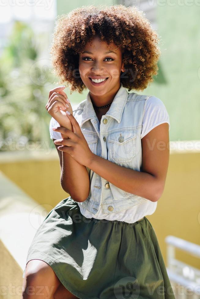 joven mujer negra, peinado afro, sonriendo en el fondo urbano foto