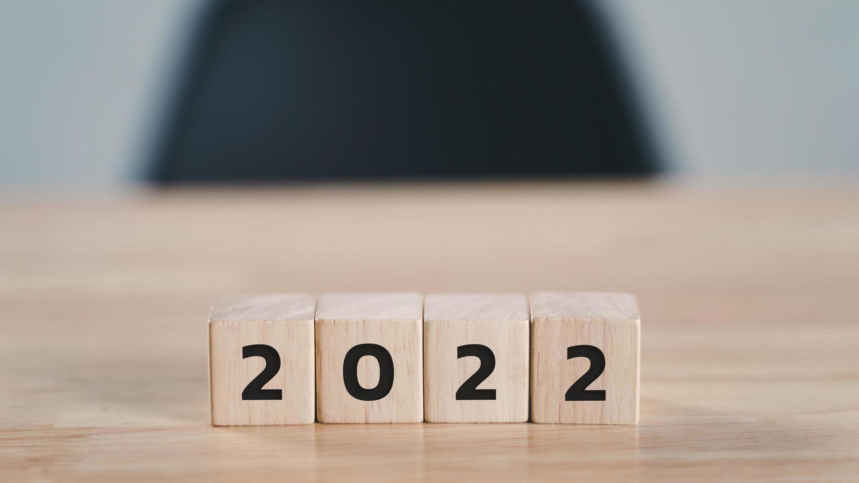 start to year 2022. wooden cube block with 2022 year text on wood table with copy space. happy new years concept. photo