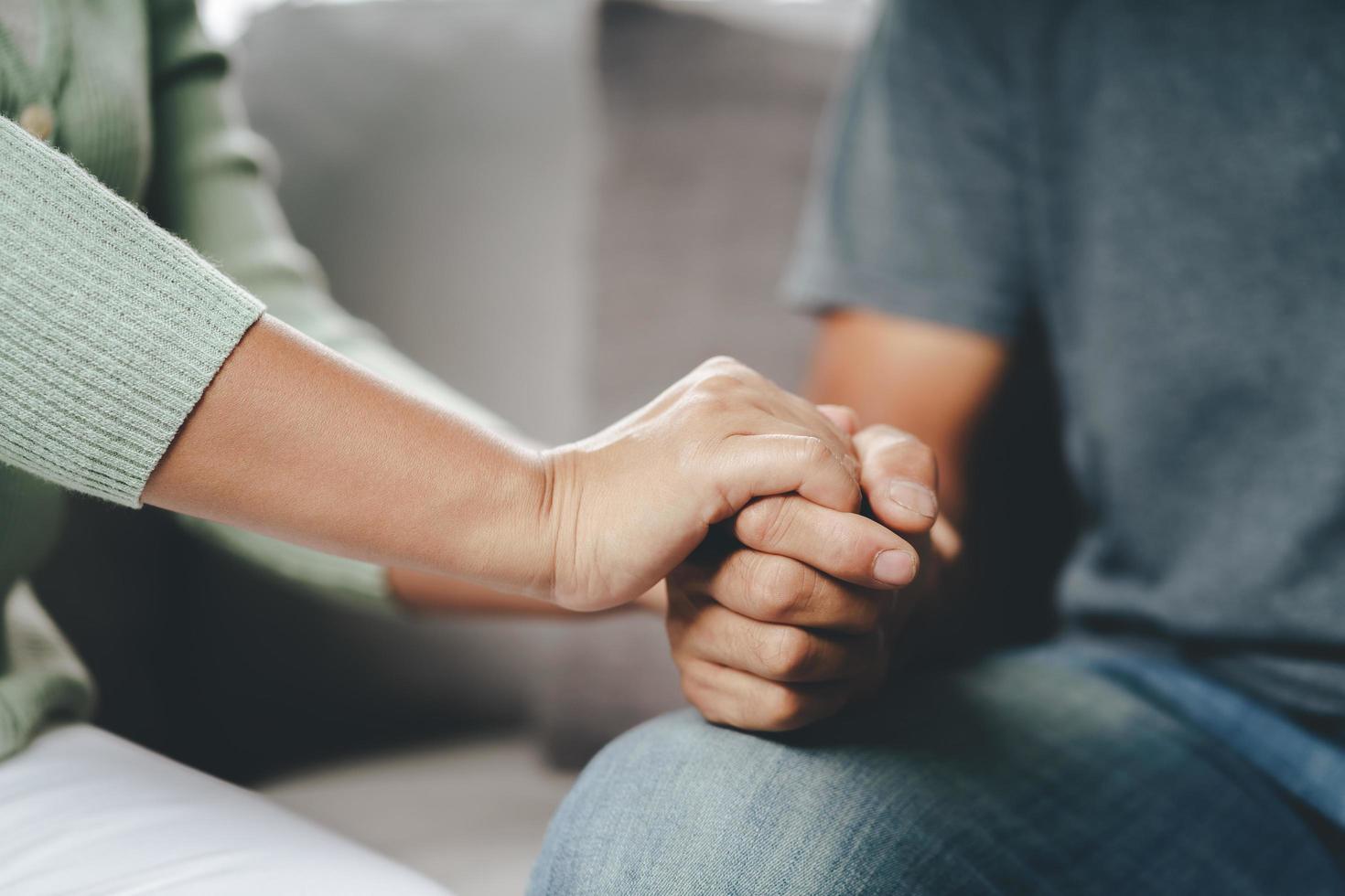 Female friend or family sitting and hold hands during cheer up to mental depress man, Psychologist provides mental aid to patient. PTSD Mental health concept photo