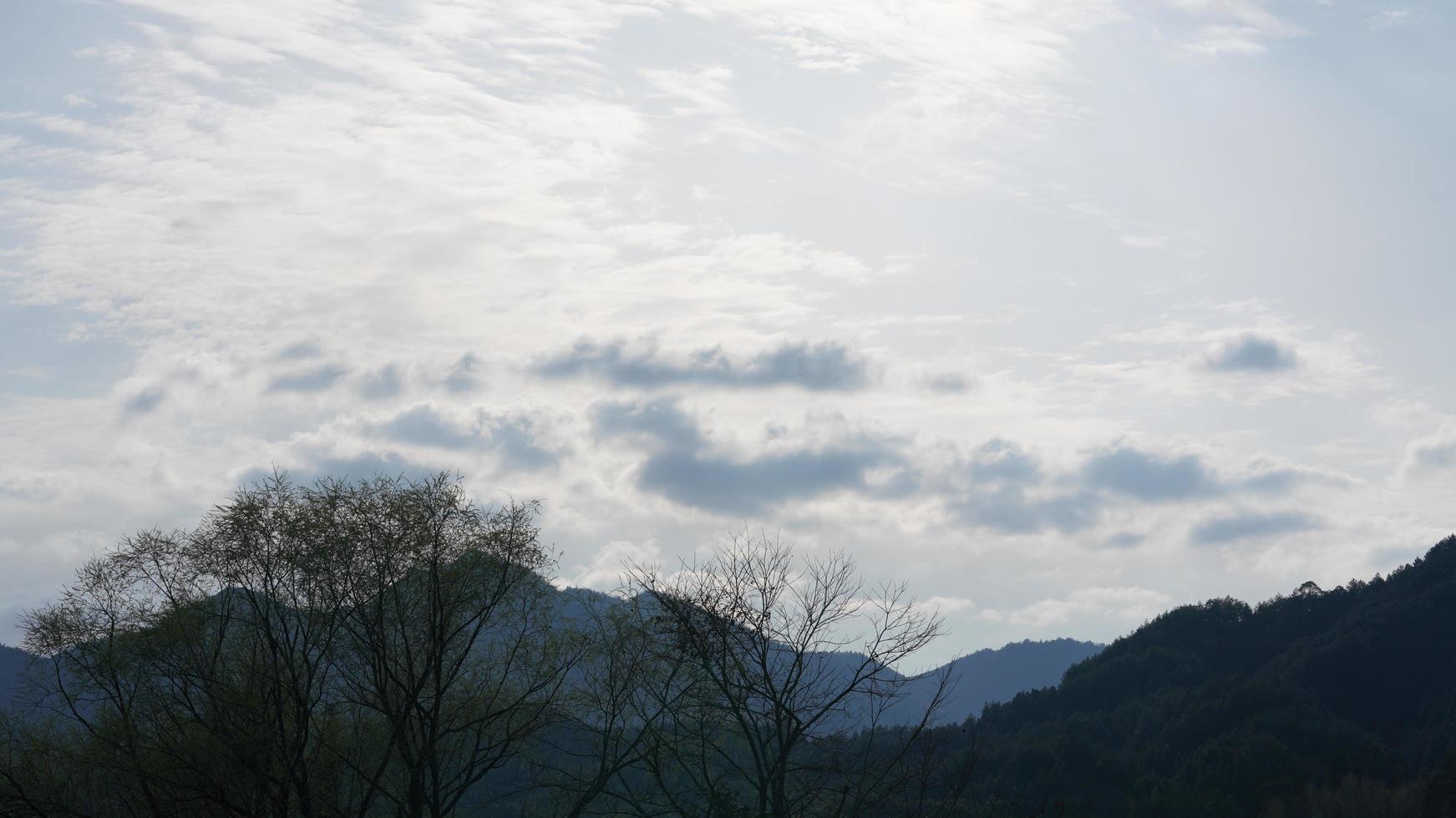 The beautiful mountains view with the green forest and clouds rising up from them  in the rainy day in the countryside of the southern China photo