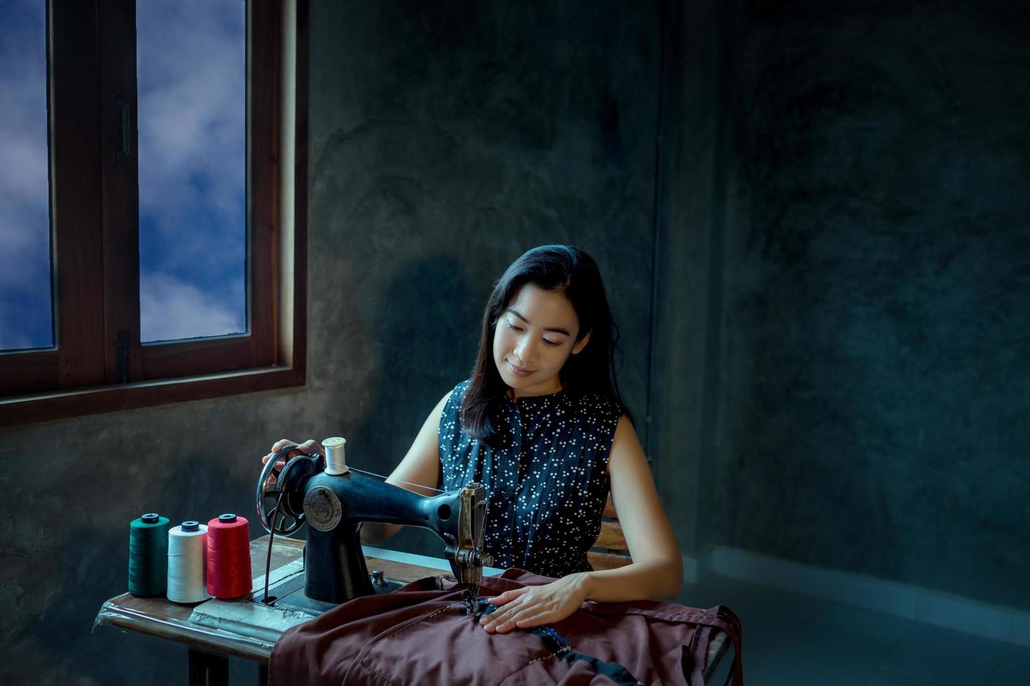 Asian girl enjoying and  sitting with sewing machine with ancient sewing machine. photo