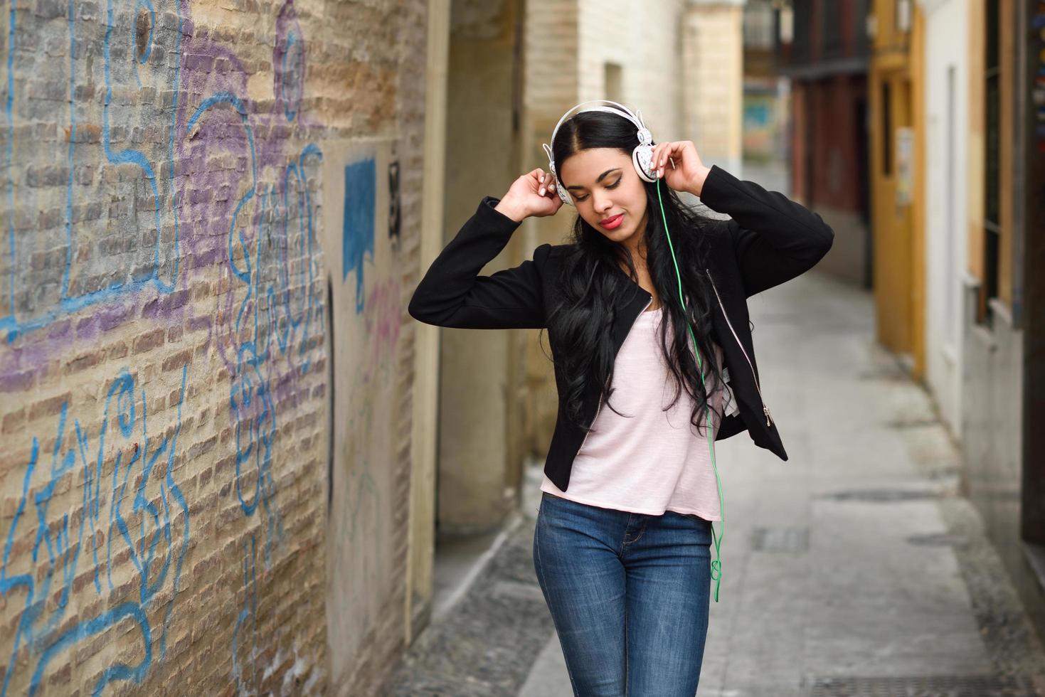 Woman in urban background listening to music with headphones photo