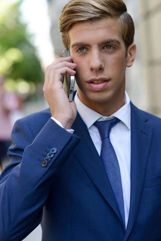 Attractive young businessman on the phone in urban background photo