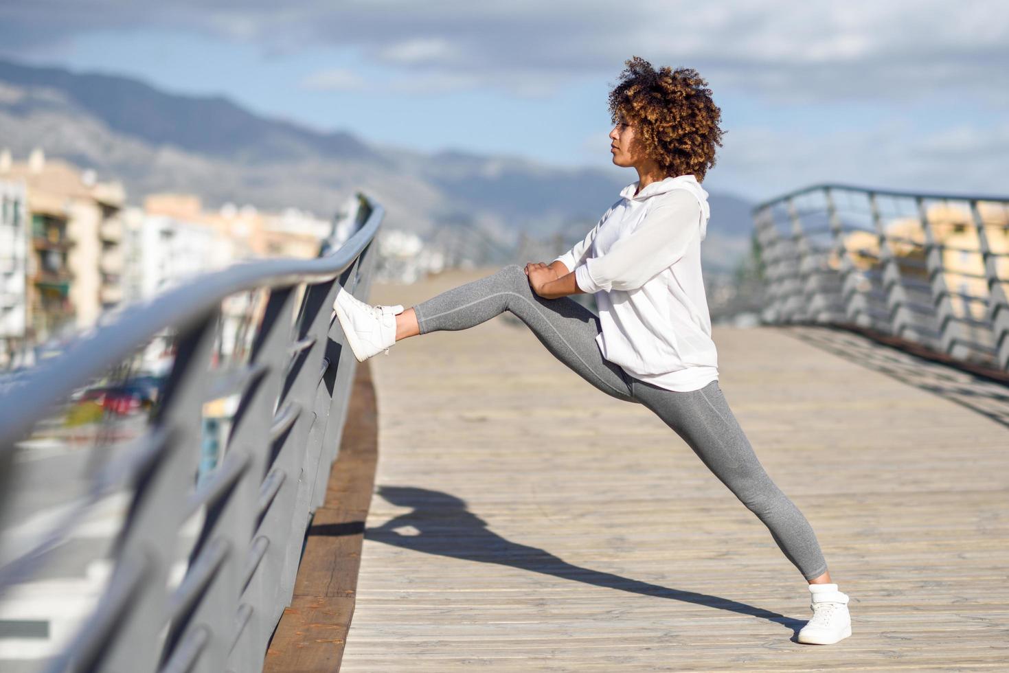 Young black woman doing stretching after running outdoors photo