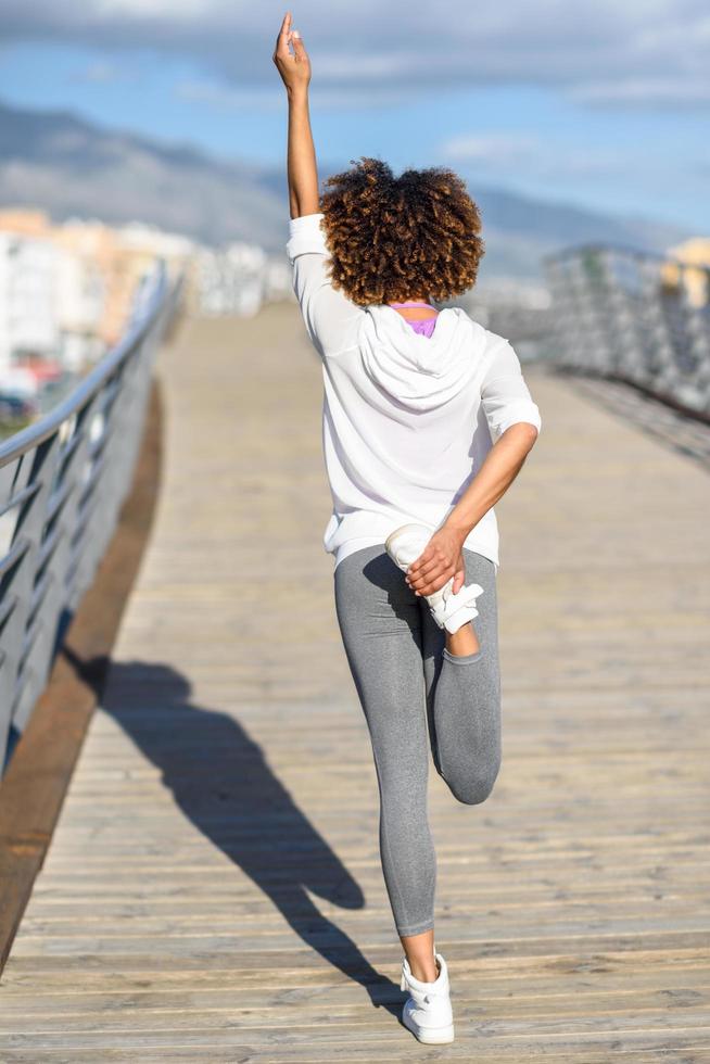 Young black woman doing stretching after running outdoors photo
