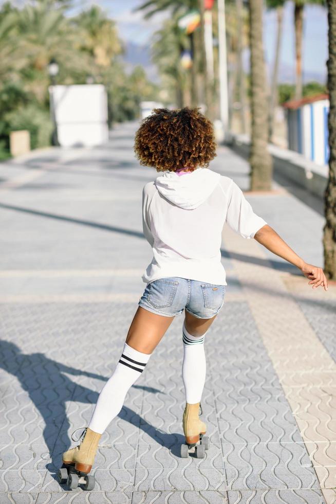 Black woman on roller skates rollerblading in beach promenade with palm trees photo