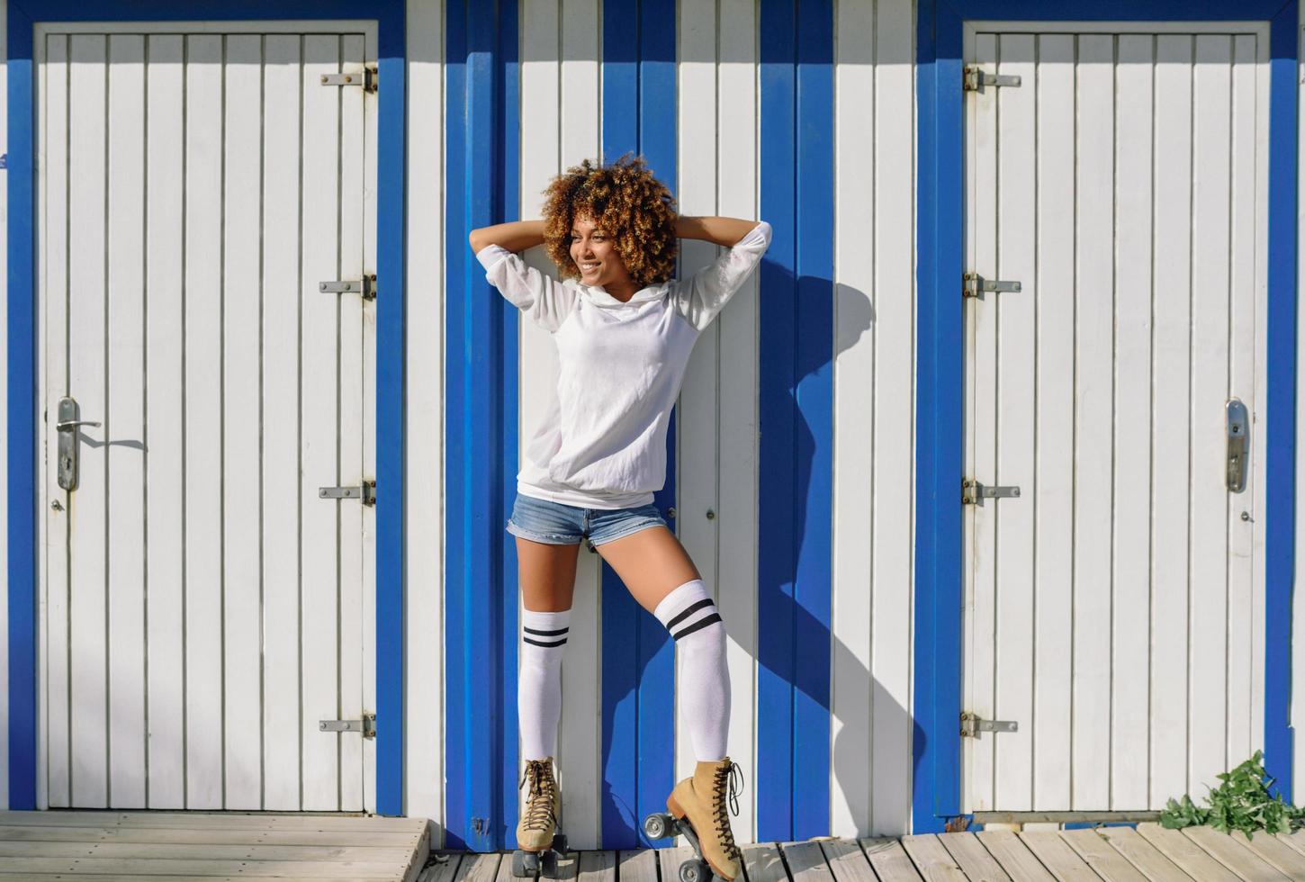 Young black woman on roller skates near a beach hut. photo