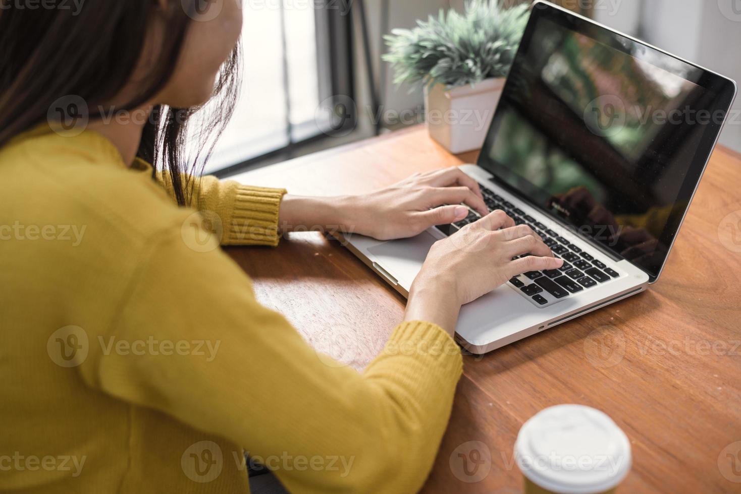 Business Technology Concepts - Digital lifestyle working outside office. Woman hands typing laptop computer with blank screen on table in coffee shop. Blank laptop screen mock up for display of design photo