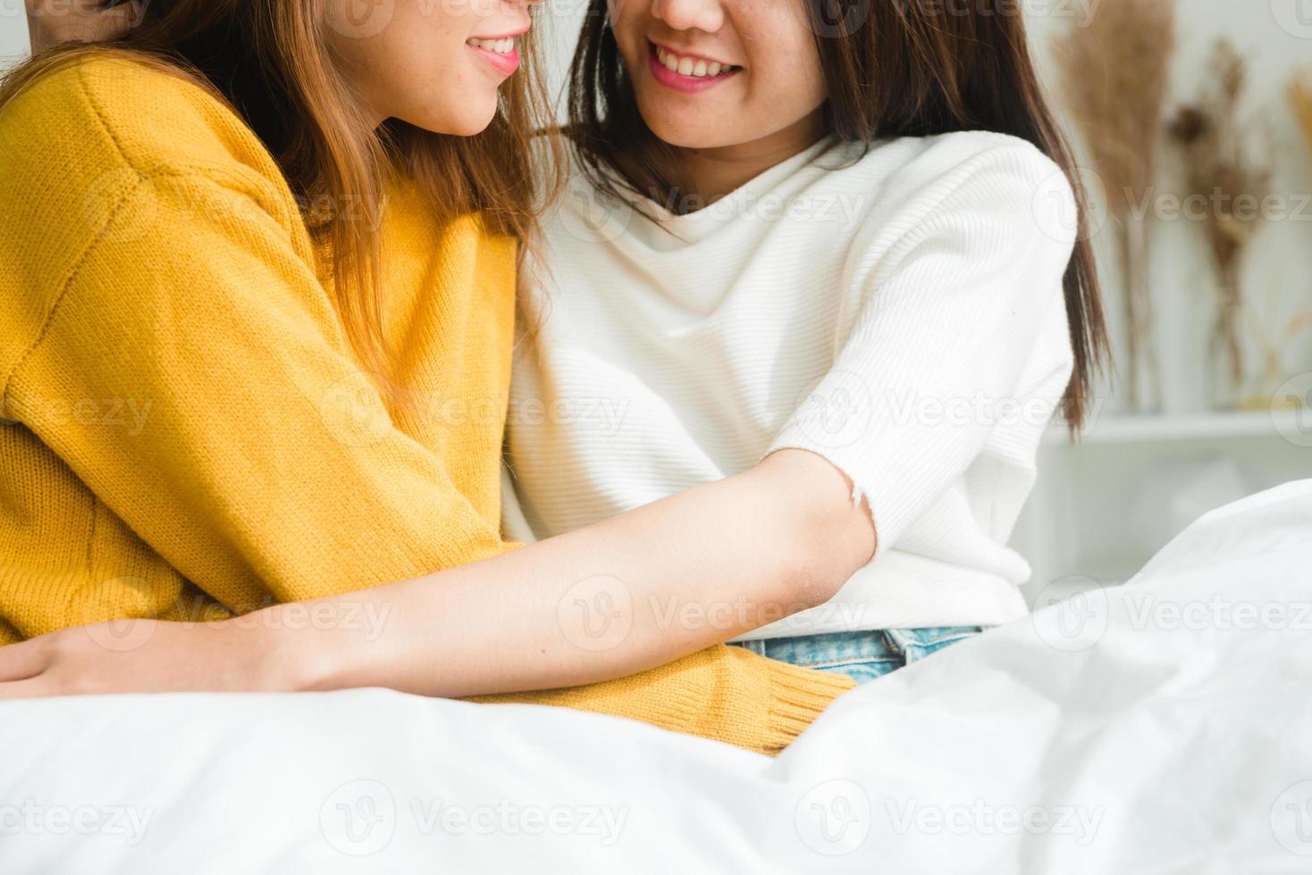 Beautiful young asian women LGBT lesbian happy couple sitting on bed hugging and smiling together in bedroom at home. LGBT lesbian couple together indoors concept. Spending nice time at home. photo