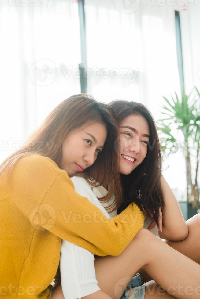 hermosas mujeres asiáticas jóvenes lesbianas lgbt pareja feliz sentada en la cama abrazándose y sonriendo juntos en el dormitorio en casa. Pareja de lesbianas lgbt juntos en el interior concepto. pasar un buen rato en casa. foto