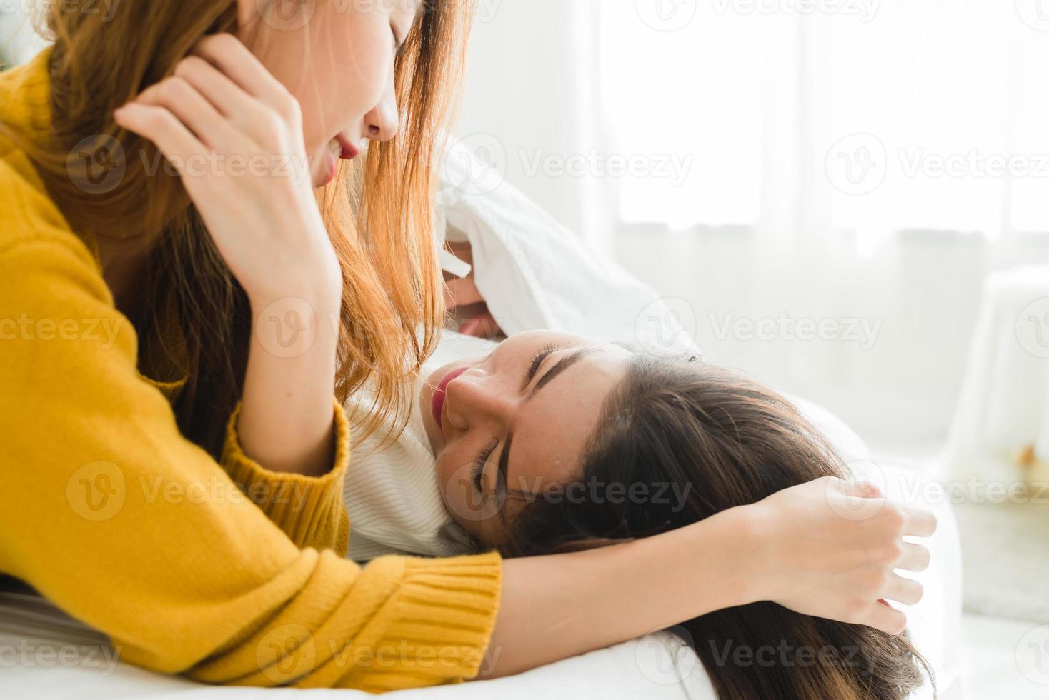 Beautiful young asian women LGBT lesbian happy couple hugging and smiling while lying together in bed under blanket at home. Funny women after wake up. LGBT lesbian couple together indoors concept. photo