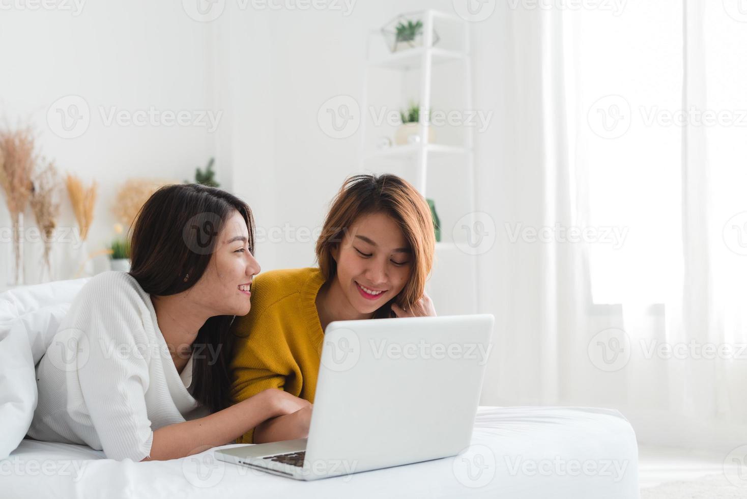 hermosas mujeres asiáticas jóvenes lgbt lesbiana pareja feliz sentada en la cama abrazo y usando la computadora portátil juntos dormitorio en casa. Pareja de lesbianas lgbt juntos en el interior concepto. pasar un buen rato en casa. foto