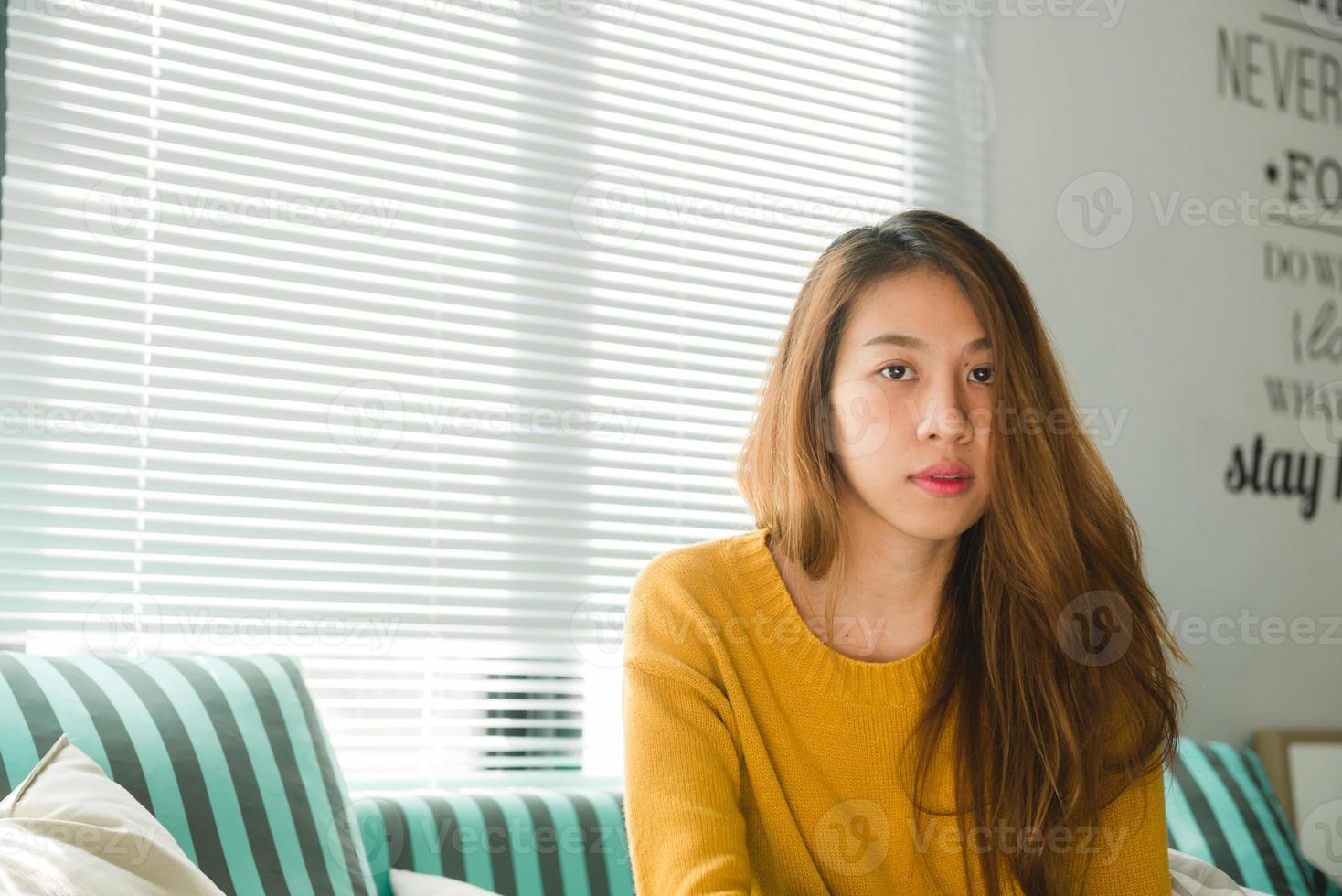 Portrait of happy home owner asian woman with perfect teeth smiling sitting on sofa in the living room in house interior. Relaxing asian woman sitting comfortable in sofa lounge chair smiling happy. photo