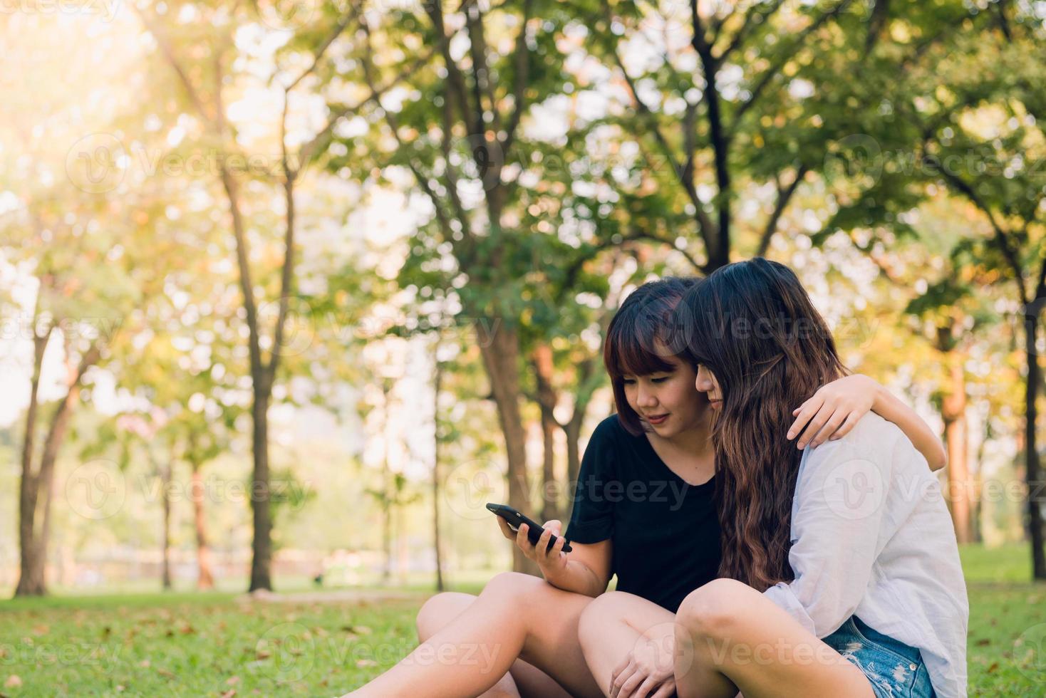 Two beautiful happy young asian women friends having fun together at park and taking a selfie. Happy hipster young asian girls smiling and looking at smartphone. Lifestyle and friendship concepts. photo