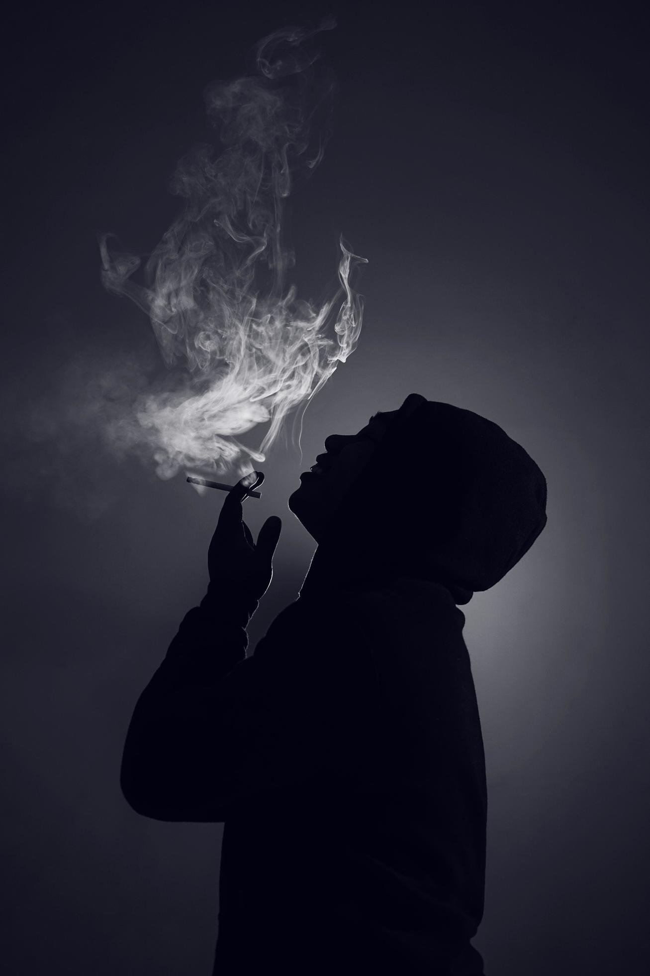 Indonesia, 21122021 - a silhouette of a man with hoodie is smoking ...