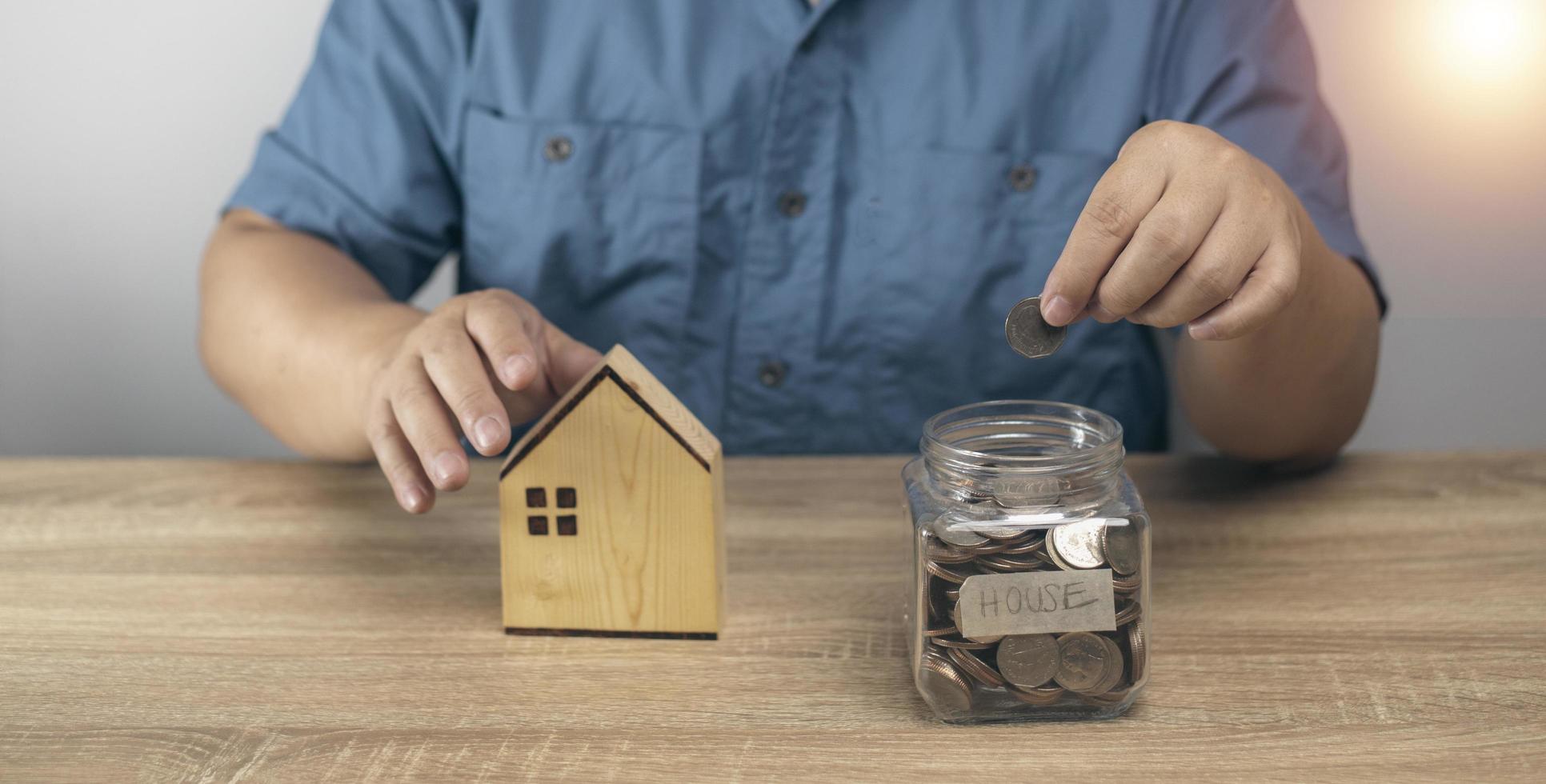 hombre poniendo dinero en el banco frasco para ahorrar para futuras compras de vivienda. planificación de ahorro de dinero, negocios, finanzas, pautas de pago, concepto financiero. foto