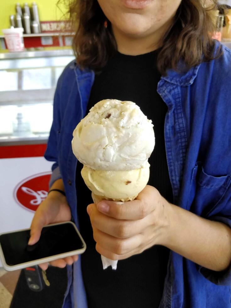 ice cream flavor vanilla frozen dessert pattern in waffle cone hand holding on table. photo