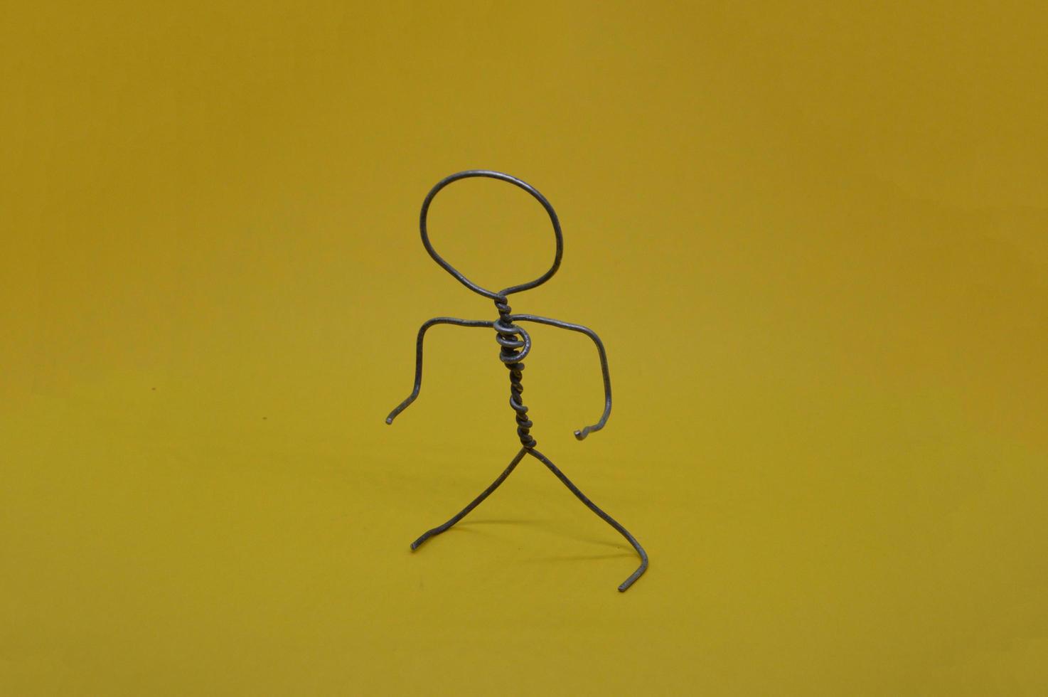 Metal man made of wire stands on yellow background photo