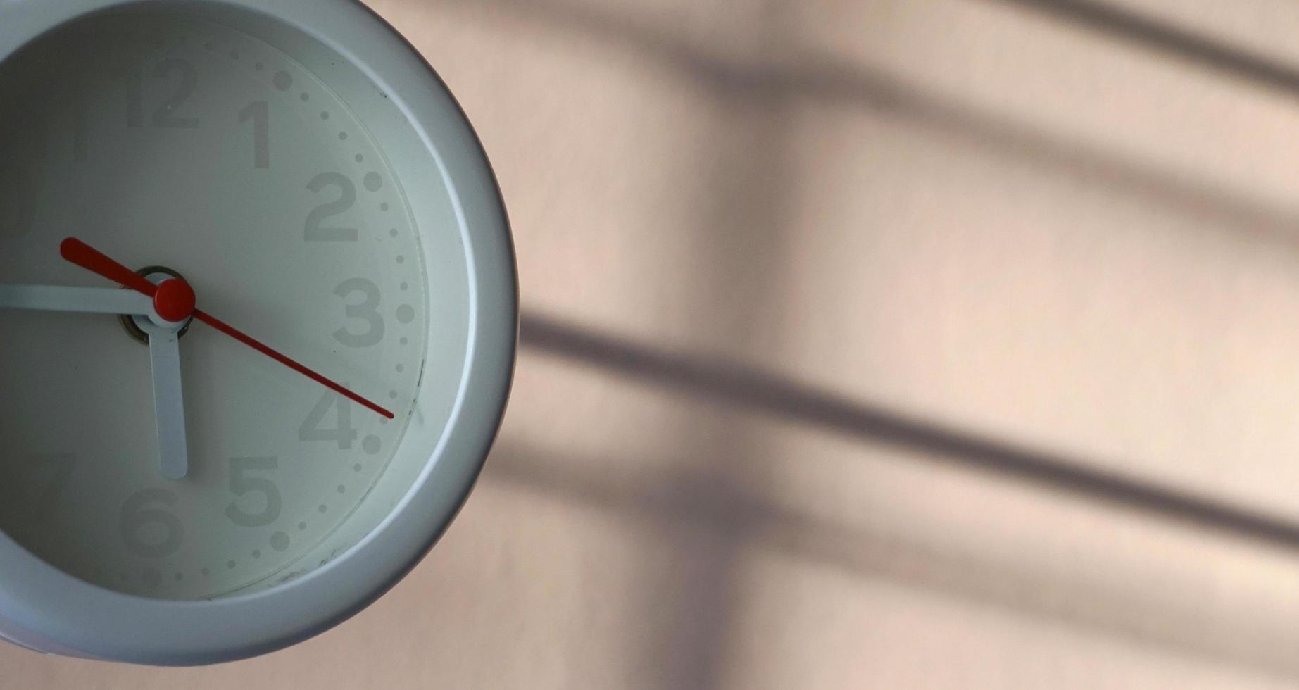 A closeup shot of a white clock with arrows showing time. photo