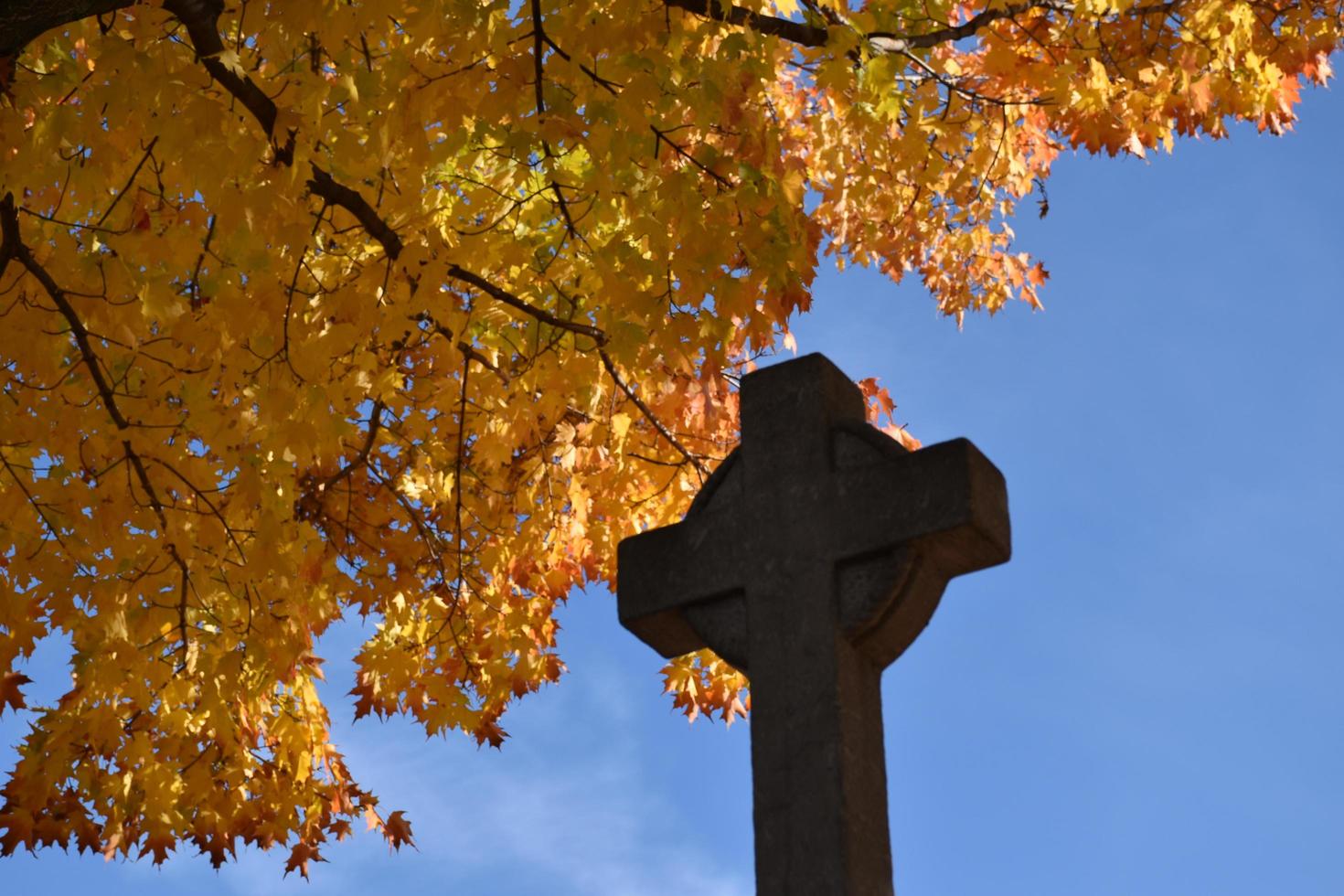 una cruz en un cementerio en el otoño foto