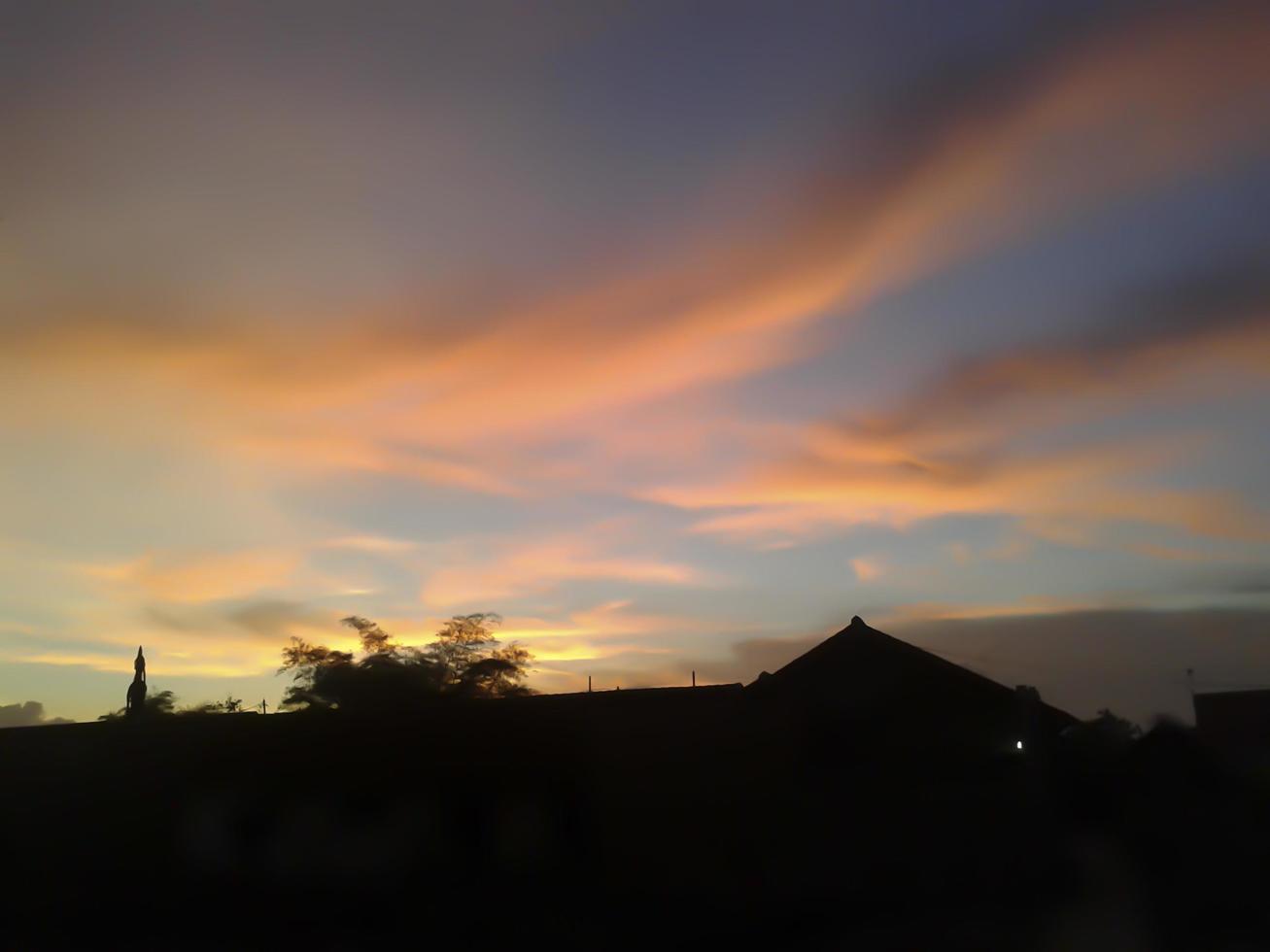 Dramatic sky. Red sunset clouds over trees an home. Setting sun and late afternoon. Feelings of peace and infinity. photo