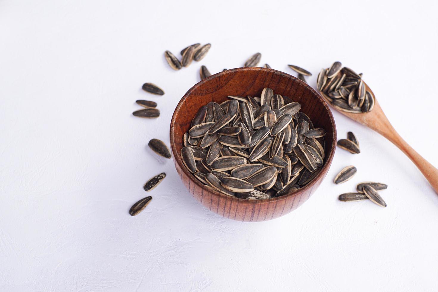 Sunflower seeds in a wooden bowl on a white table photo