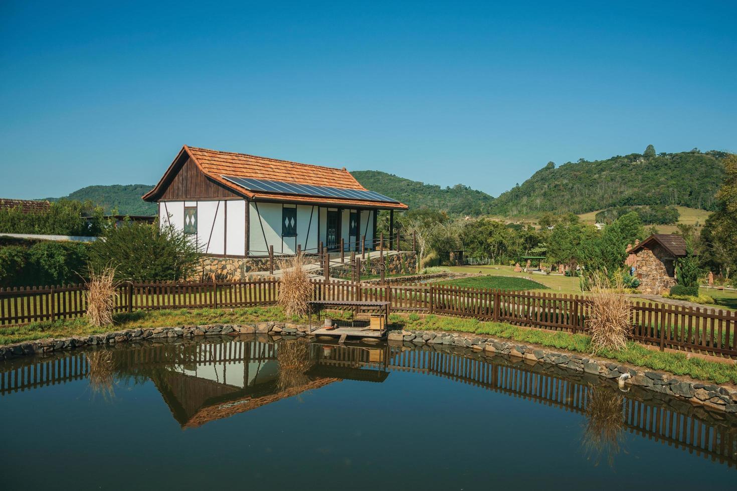 nova petropolis, brasil - 20 de julio de 2019. casa de estilo típico con estanque en medio de un paisaje rural en el parque de esculturas piedras del silencio cerca de nova petropolis. una hermosa ciudad rural fundada por inmigrantes alemanes. foto