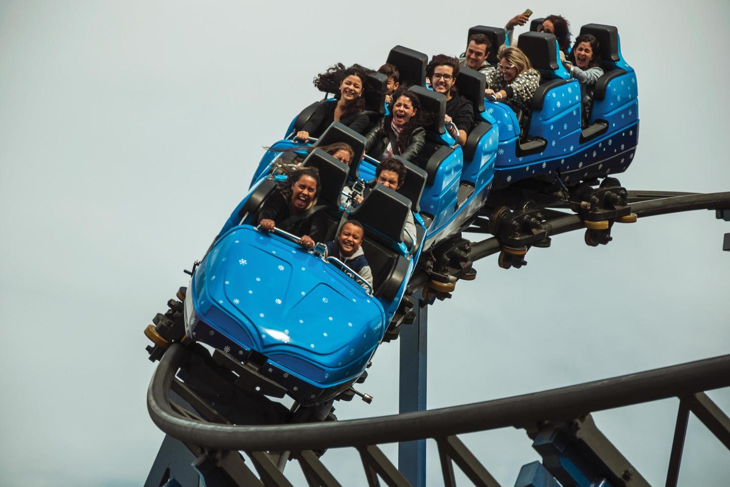 Canela, Brazil - July 21, 2019. People in a blue cart having fun on roller coaster in a cloudy day at the Alpen amusement park near Canela. A charming small town very popular by its ecotourism. photo