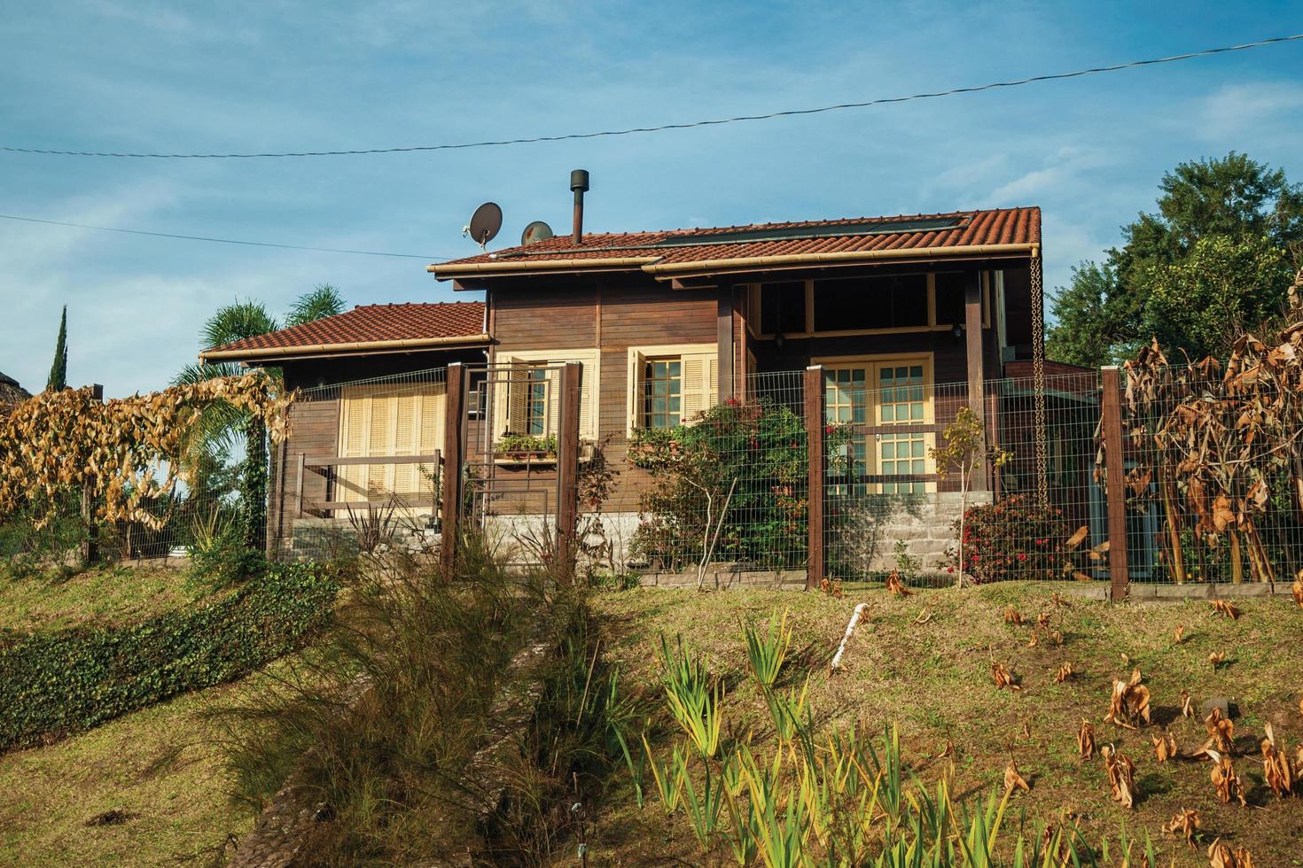 bento goncalves, brasil - 13 de julio de 2019. encantadora casa de madera con valla y jardín al atardecer, cerca de bento goncalves. una acogedora ciudad rural en el sur de Brasil famosa por su producción de vino. foto