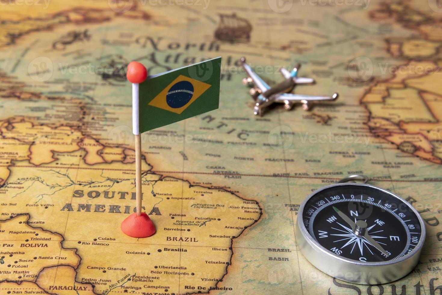 bandera de brasil, brújula y avión en el mapa mundial. foto