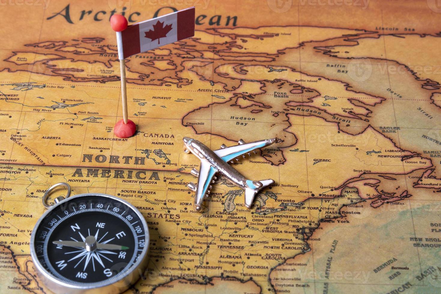 Canada flag, compass and airplane on the world map. photo