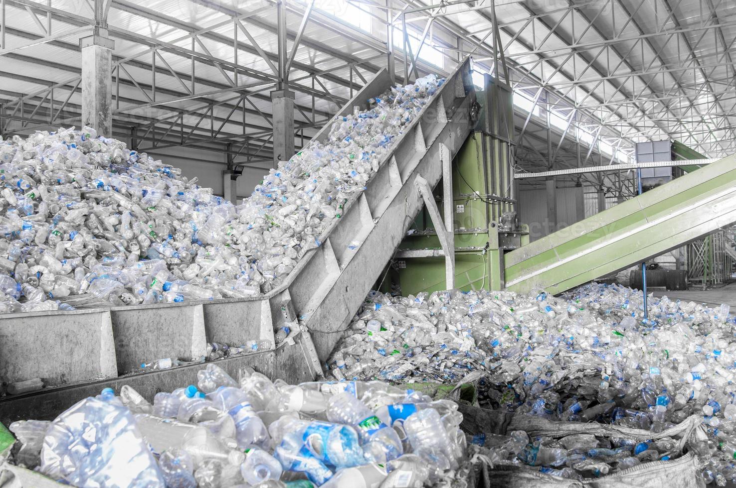 Primer plano de una escalera mecánica con un montón de botellas de plástico en la fábrica para su procesamiento y reciclaje. planta de reciclaje de mascotas foto