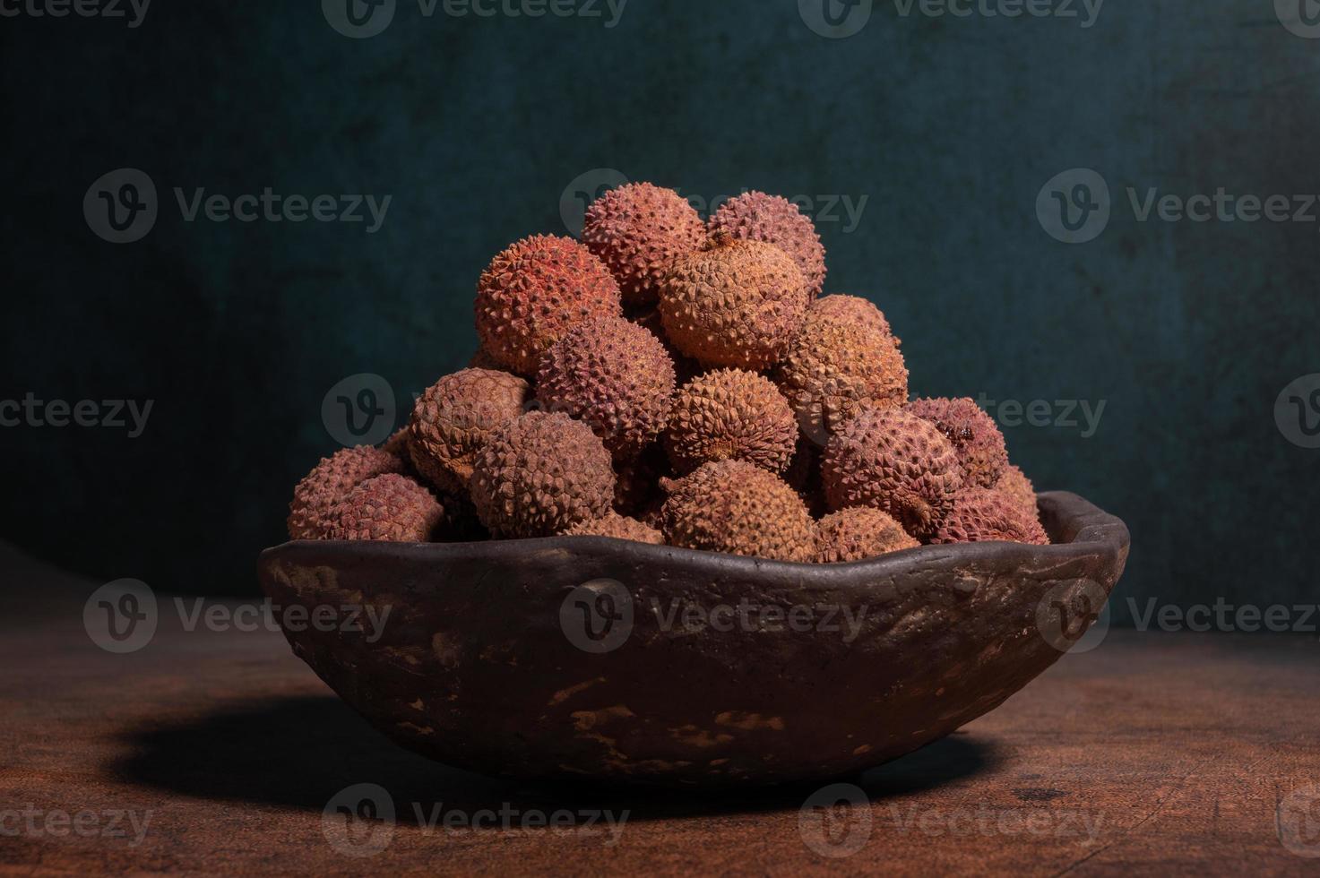 Dried litchi in a bowl on a dark yellow table photo