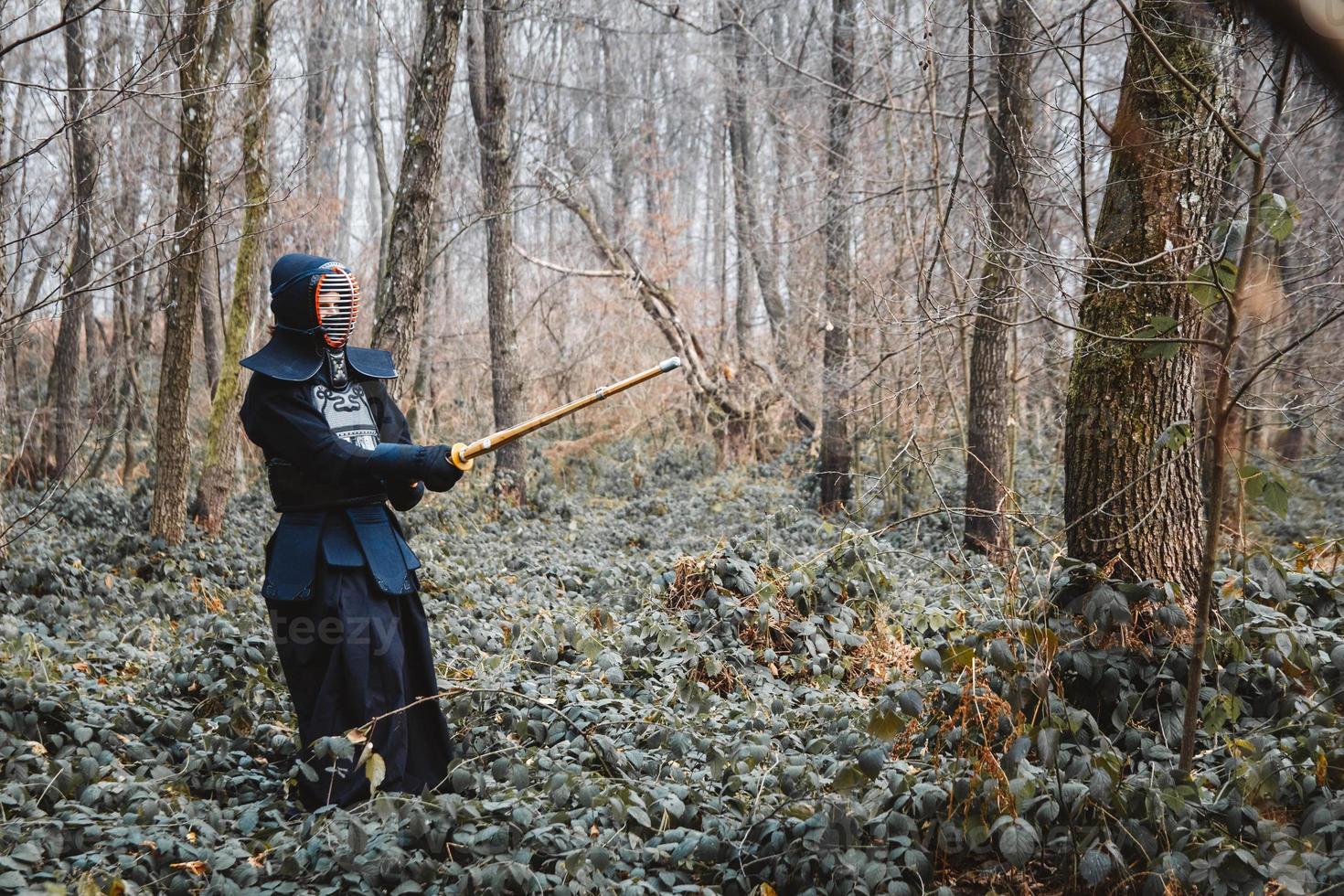 Man practicing kendo with shinai bamboo sword on forest photo