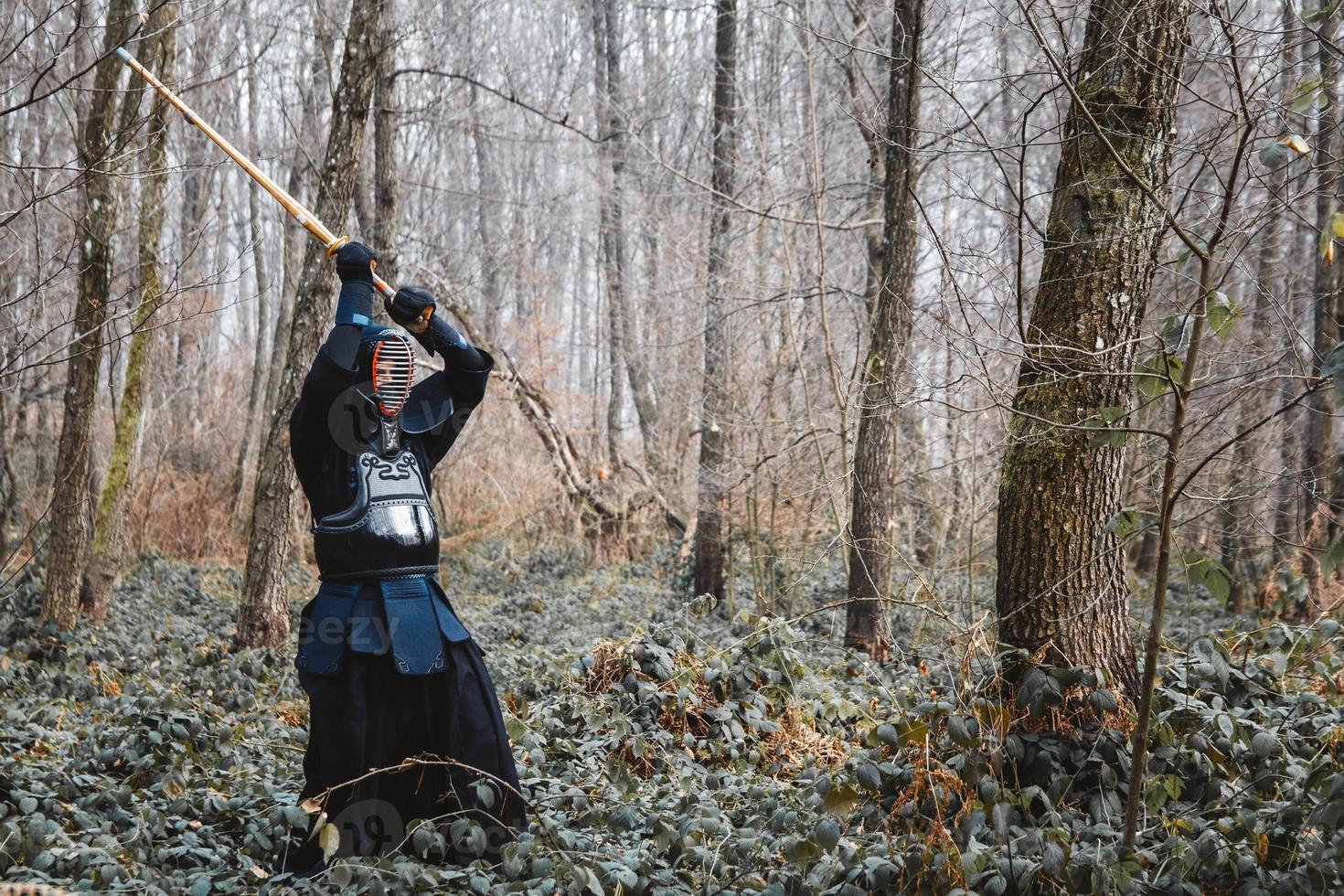 Man practicing kendo with shinai bamboo sword on forest background photo