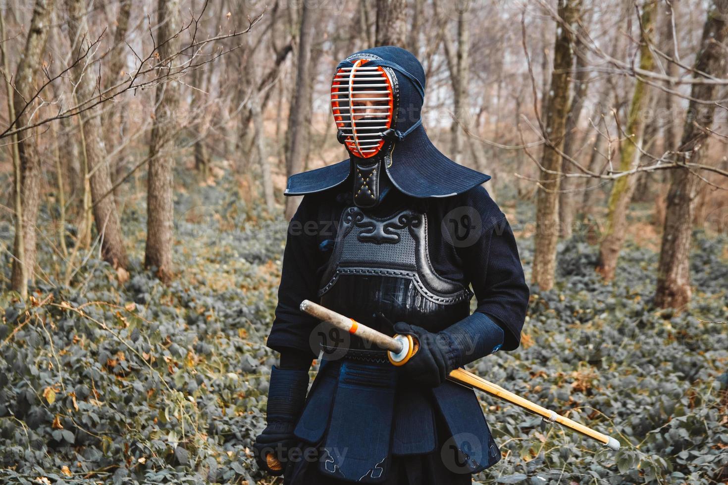 Man practicing kendo with shinai bamboo sword on forest background photo