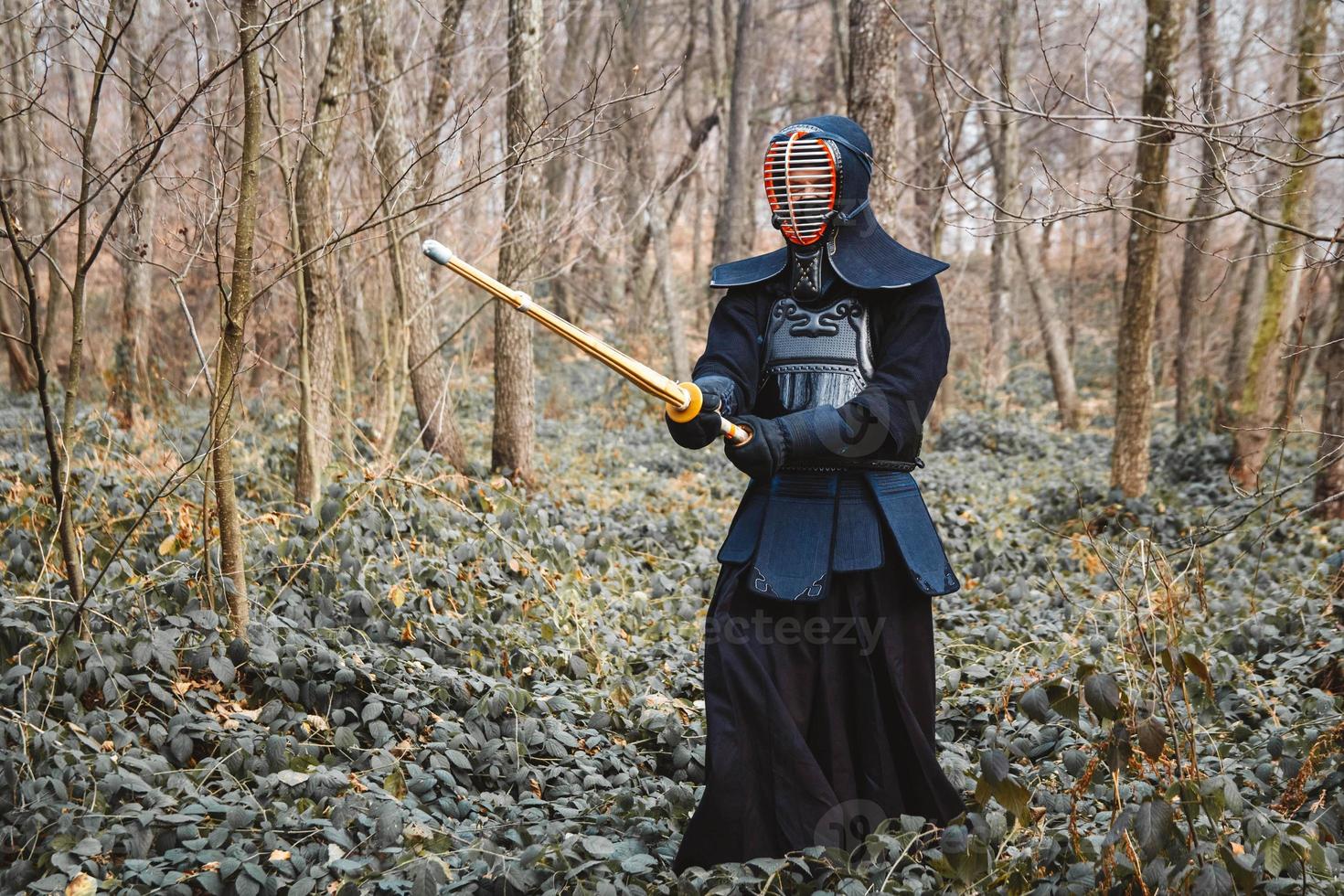 Man practicing kendo with shinai bamboo sword on forest background photo