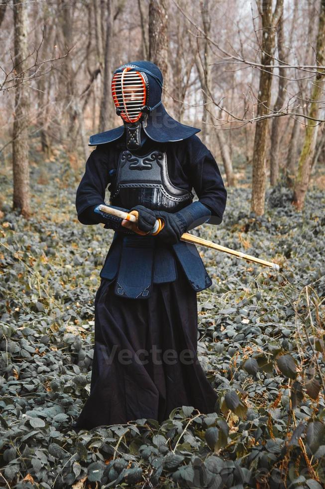 Man practicing kendo with shinai bamboo sword on forest background photo