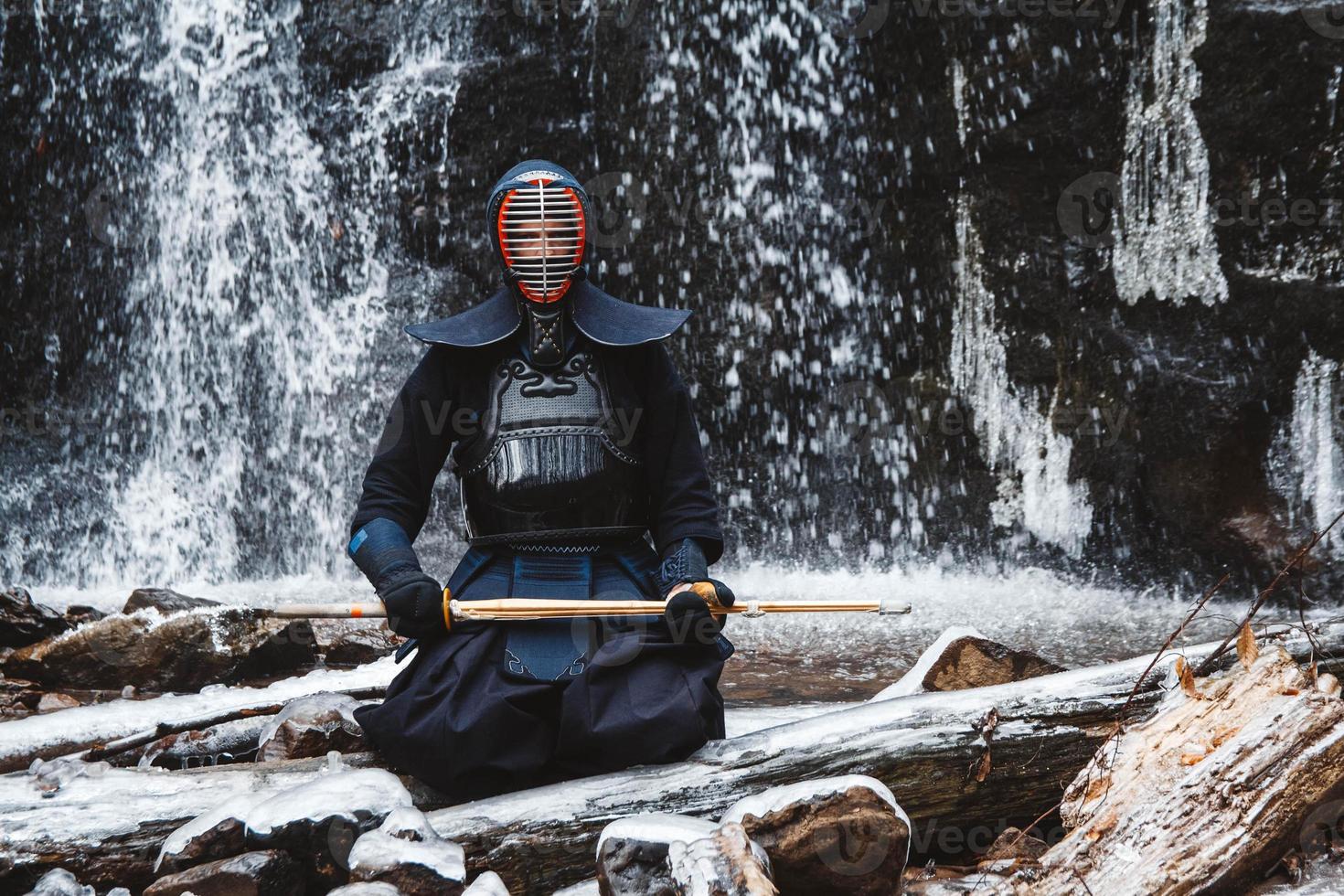 Man practicing kendo with bamboo sword on waterfall background photo