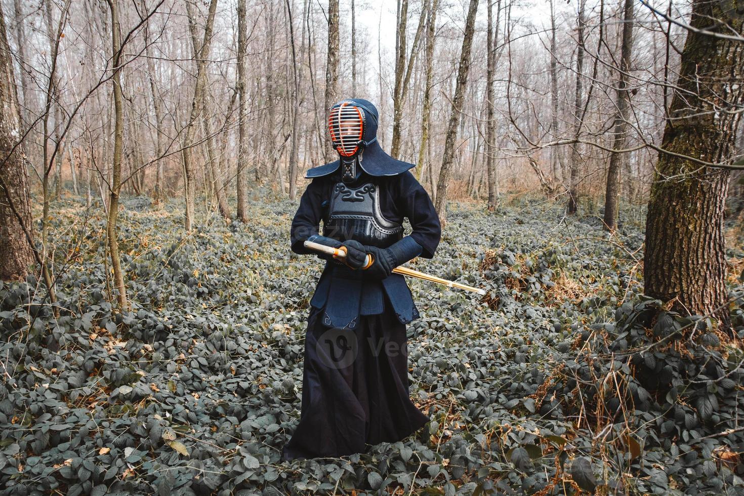 Man practicing kendo with shinai bamboo sword on forest background photo