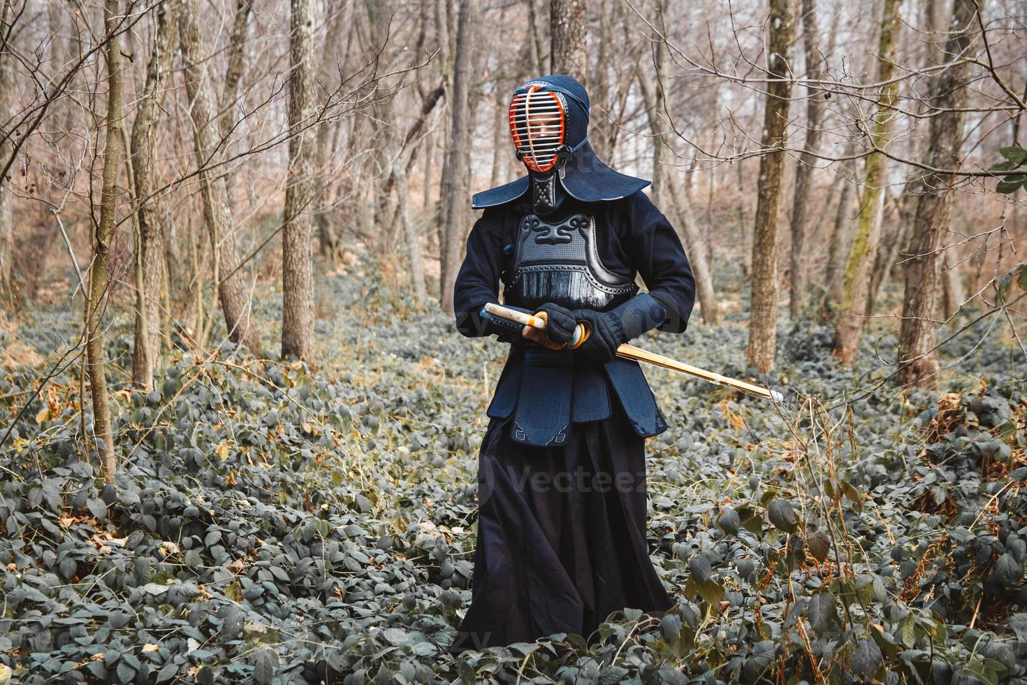 Man practicing kendo with shinai bamboo sword on forest background photo