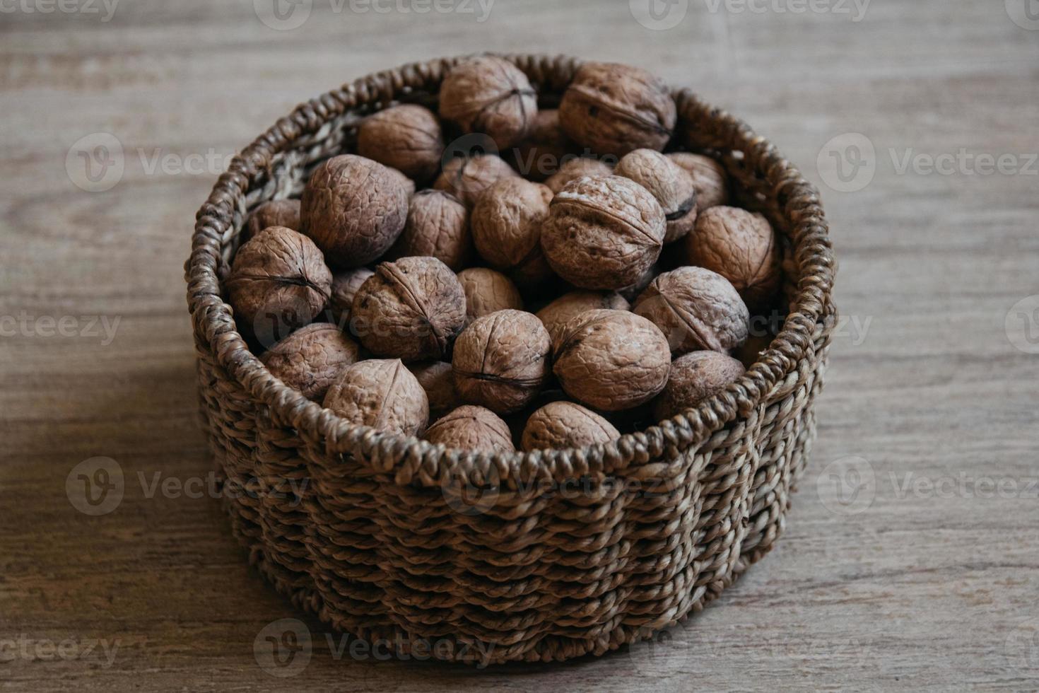 Walnuts in a round wicker basket on a wooden background photo