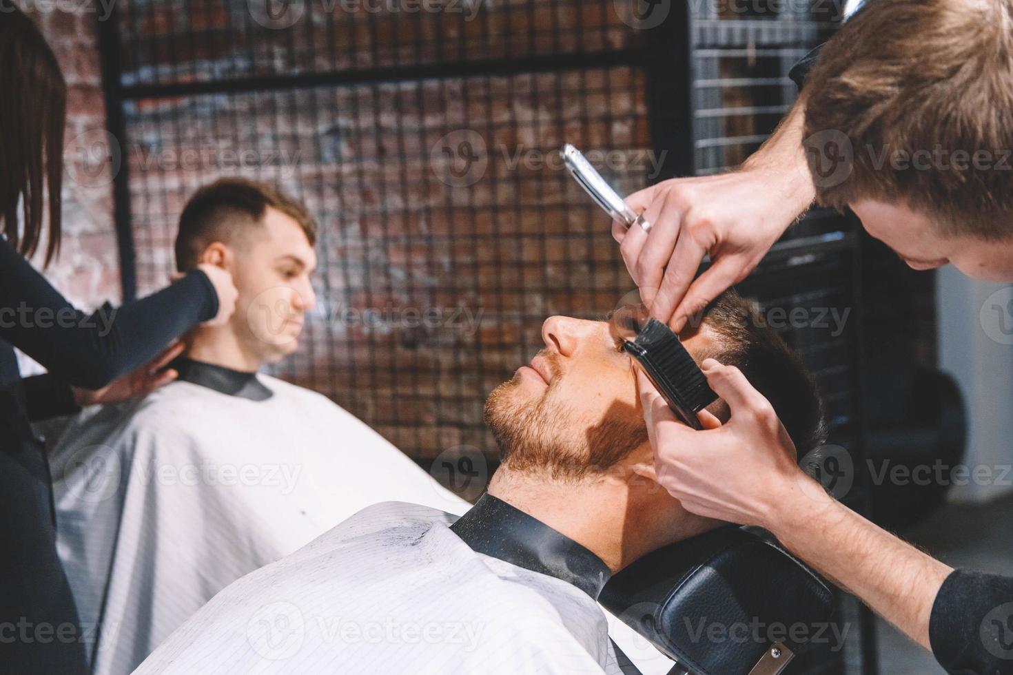 Los peluqueros cortan a sus clientes en la barbería. concepto de publicidad y peluquería. foto