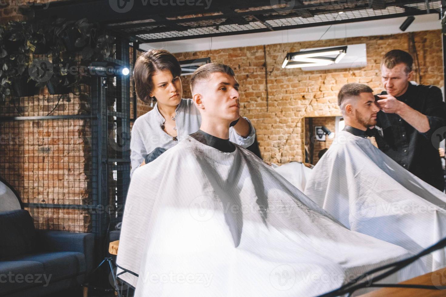 Los peluqueros cortan a sus clientes en la barbería. concepto de publicidad y peluquería. foto