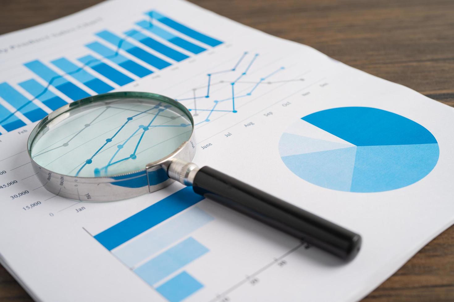 Magnifying glass on charts graphs paper. Financial development, Banking Account, Statistics, Investment Analytic research data economy, Stock exchange trading, Business office company meeting concept. photo