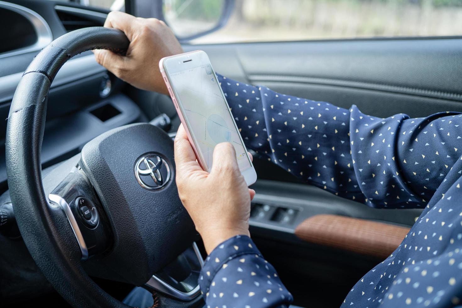 Bangkok, Thailand, July 1, 2021 Holding iPhone in toyota sienta car to communication with family and friends. photo