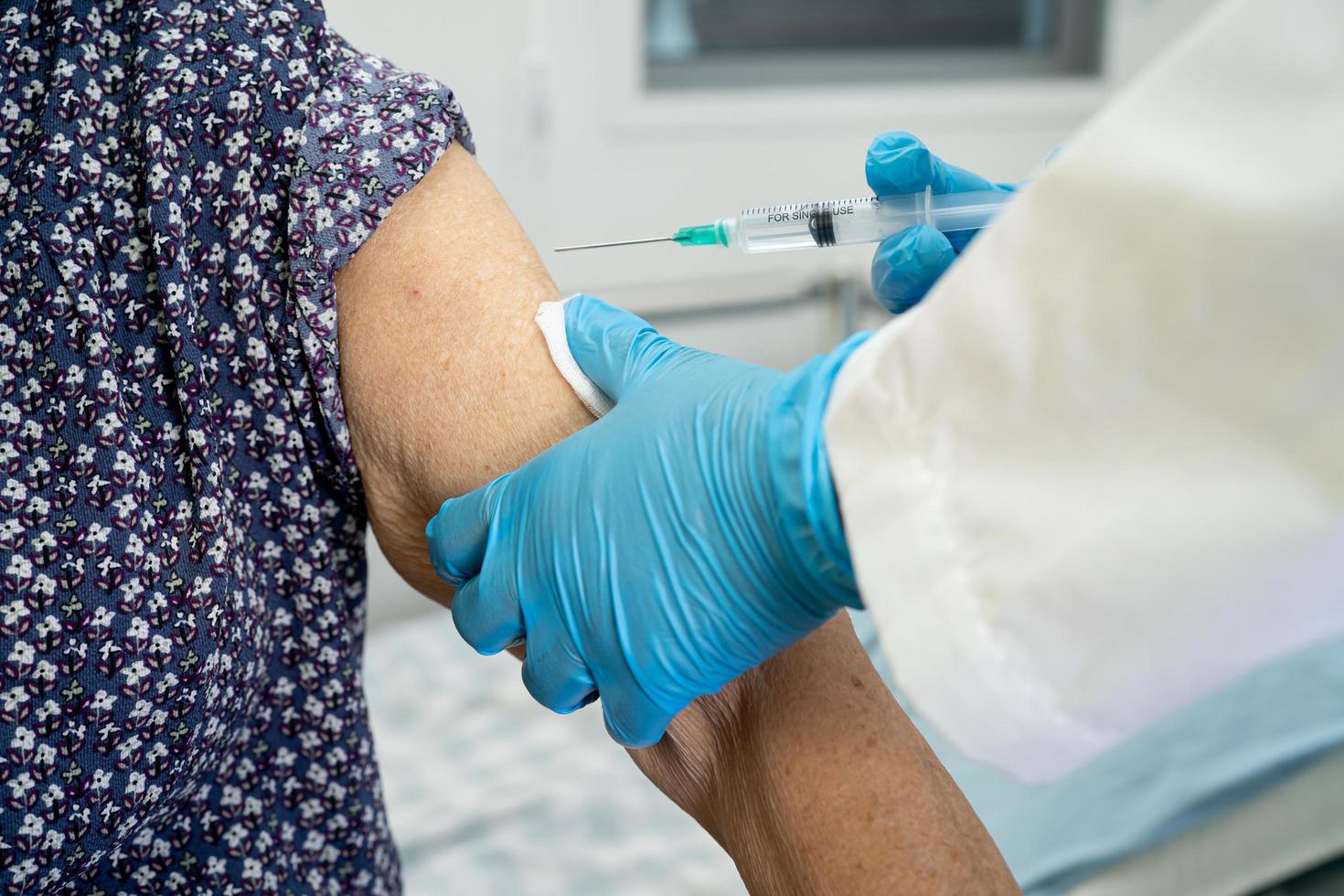 Elderly Asian senior woman wearing face mask getting covid-19 or coronavirus vaccine by doctor make injection. photo